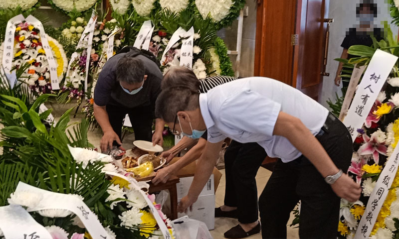 白事管家与家属在告别厅整理祭品